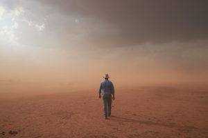 A photograph of a man in a drought afflicted landscape
